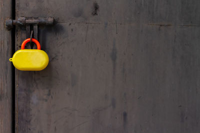 Yellow padlock toy hanging on wall