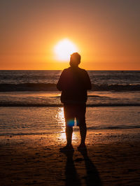 Silhouette man standing on beach during sunset