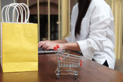 Midsection of woman standing by table at store