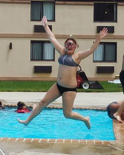 Happy young woman jumping in swimming pool