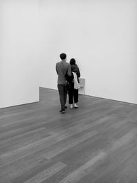 Rear view of man and woman standing on floor against wall