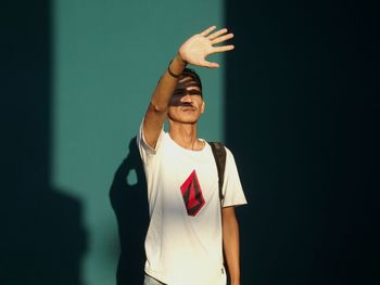 Man shielding eyes while standing against wall