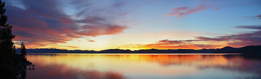 Scenic view of lake against dramatic sky during sunset