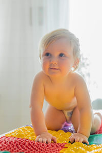 The kid walks barefoot on multi-colored massage rugs.