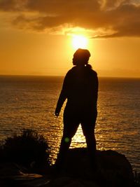 Silhouette man looking at sea against sky during sunset