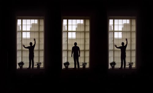 Multiple image of silhouette man standing on window sill