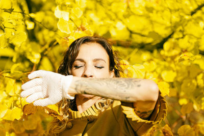 Woman covering her mouth with her tattooed forearm iii