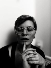 Portrait of woman wearing eyeglasses against wall