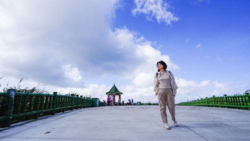 Full length of a woman standing on road against sky