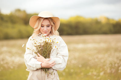 Smiling woman holding flowers on field