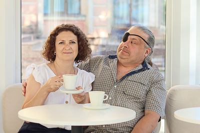 Portrait of smiling friends using mobile phone at home
