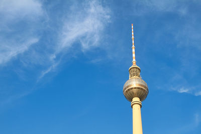 Low angle view of communications tower against blue sky during sunny day