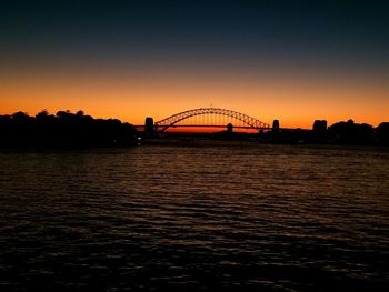 Silhouette bridge over river against sky during sunset