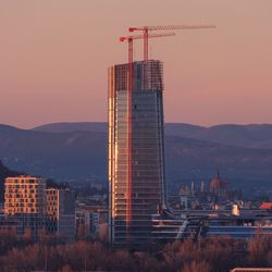 Modern buildings in city against sky during sunset