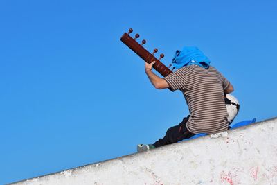 Low angle view of man against blue sky