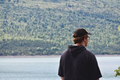 Rear view of man looking at lake by mountain