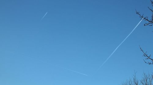 Low angle view of vapor trail against clear blue sky