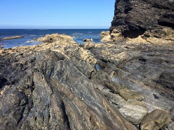 Rock formations on shore against clear sky