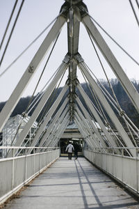 Rear view of people walking on bridge against sky