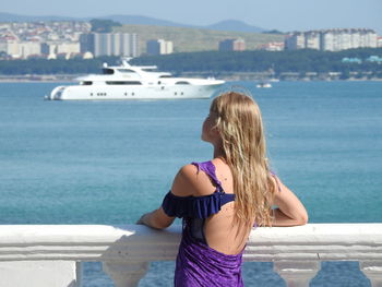 Rear view of girl standing by railing over sea