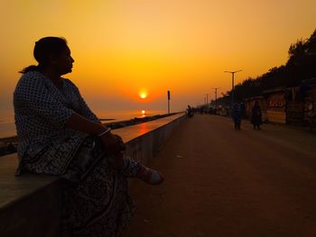 Man on beach against sky during sunset