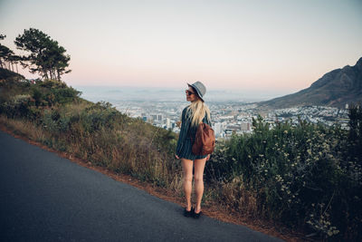 Woman walking on road against clear sky