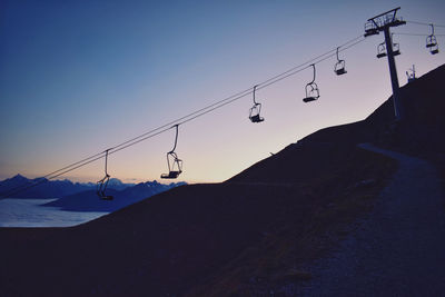 Low angle view of overhead cable cars against sunset sky