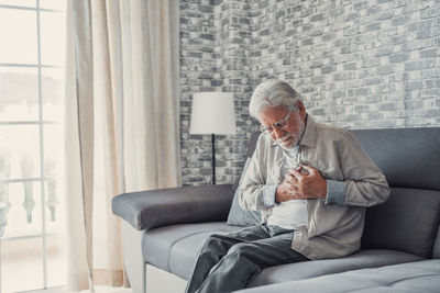 Young woman using mobile phone while sitting on sofa at home