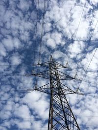 Low angle view of electricity pylon against cloudy sky