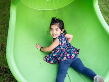 Portrait of smiling girl sliding at park