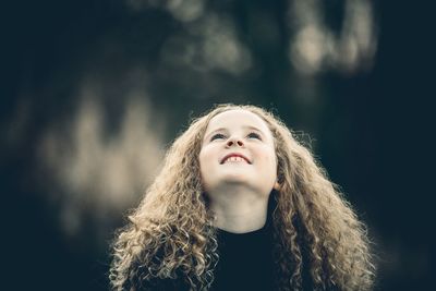 Close-up of smiling girl looking up while standing outdoors