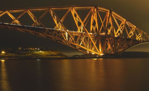 Illuminated bridge over river at night