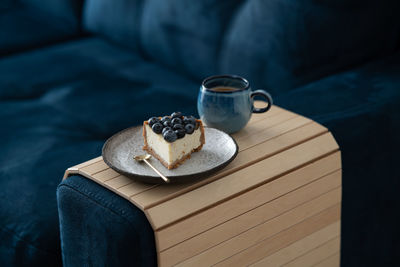 A piece of blueberry cheesecake and a cup of coffee on the couch. cozy room with a reading nook