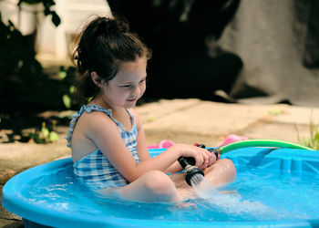 Siblings playing near a water basin in the back yard