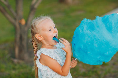 Cute girl eating cotton candy in park