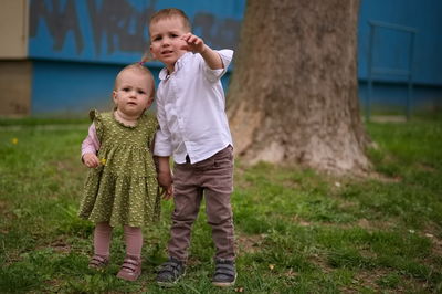 Little brother and sister standing in the park