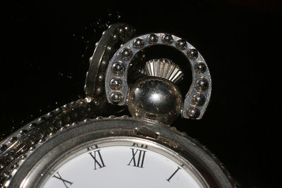 Close-up of antique pocket watch against black background