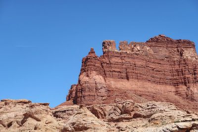 Low angle view of rock formation against clear blue sky