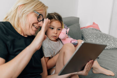 Young woman using laptop while sitting on sofa at home