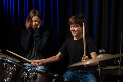 Boy playing drum sitting by teacher