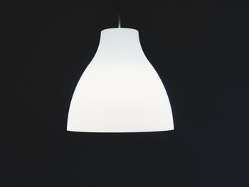 Low angle view of illuminated lamp against black background