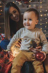 Mother and son sitting against christmas decoration