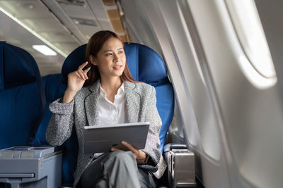 Businesswoman with digital tablet sitting in aeroplane