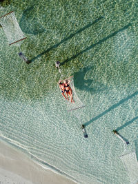 Mother and son relaxing on a hammock over the water. air view.