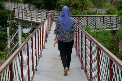 Rear view of woman walking on footbridge