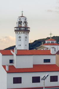 Lighthouse amidst buildings in town against sky