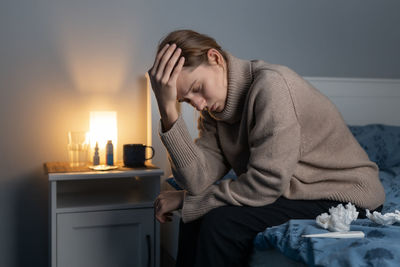 Depressed woman sitting on bed at home