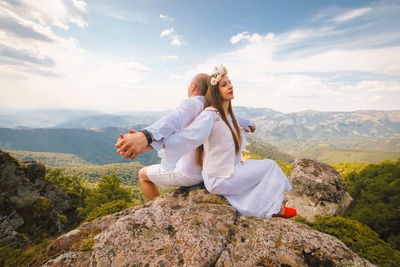 Rear view of woman on rock against mountains