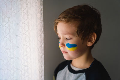 Portrait of a ukrainian boy with a face painted with the colors of the ukrainian flag.