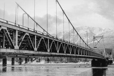 Bridge over river against cloudy sky